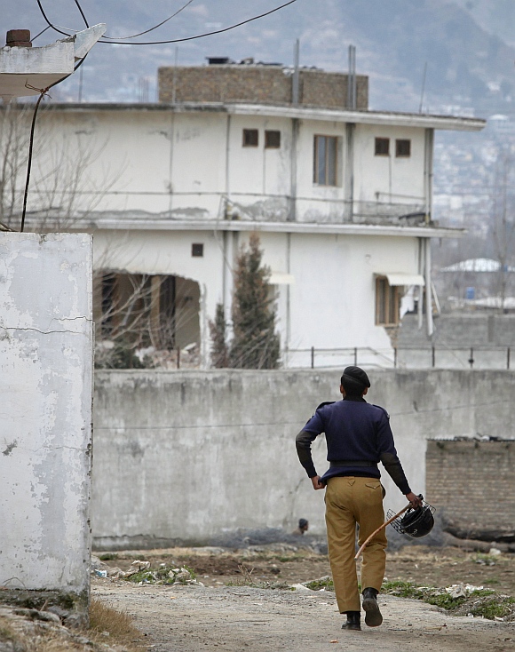 A policeman walks towards the partially demolished compound