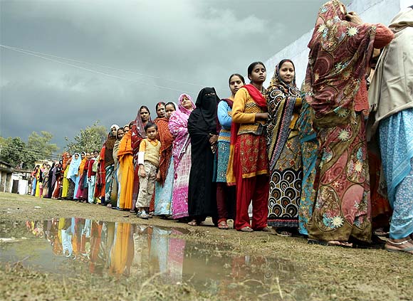 Voters line up in a queue outside a polling booth to cast their vote during the state assembly election