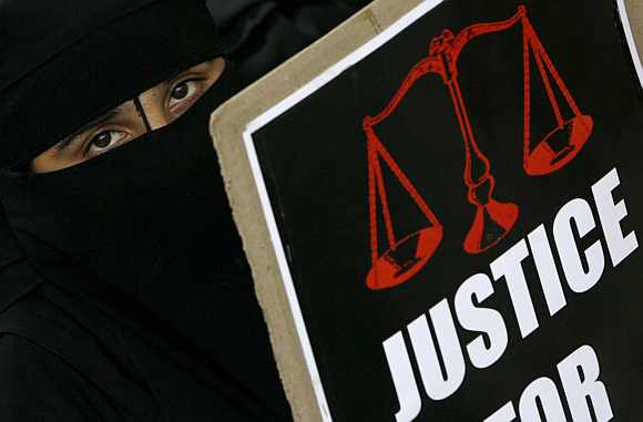 A veiled Muslim woman holds a placard during a protest