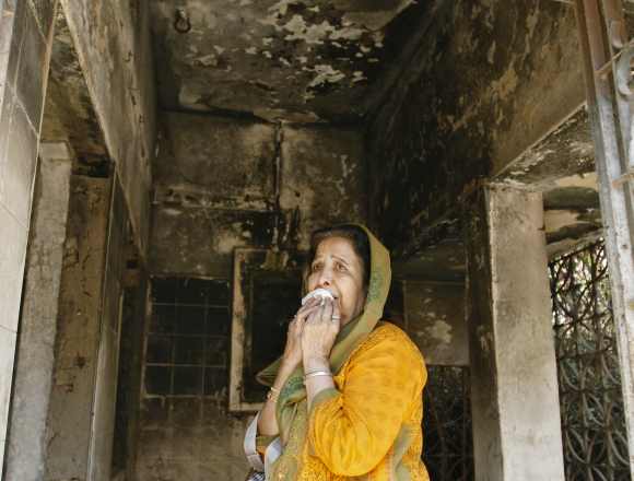 A survivor cries inside her house that was burnt and damaged during the Godhra riots during the commemoration of its 10th anniversary, in Ahmedabad