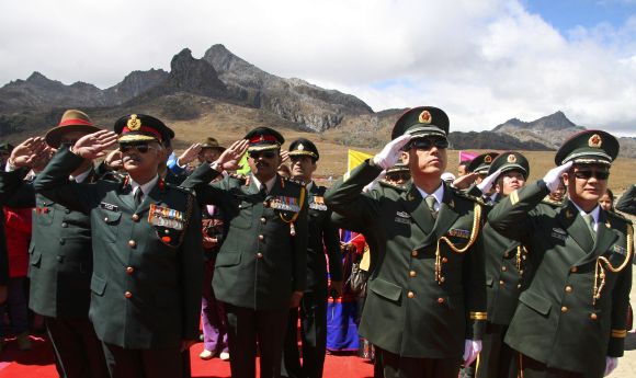 Indian and Chinese soldiers salute during celebrations to mark the 60th anniversary of the founding of the People's Republic of China, at the Indo-China border, near Tawang