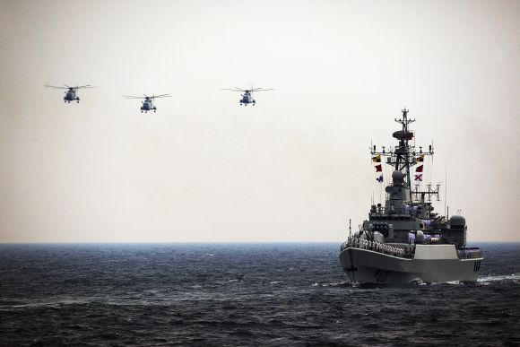 Helicopters accompany the Chinese Jiangwei II naval frigate 'Mianyang' during an international fleet review in Qingdao