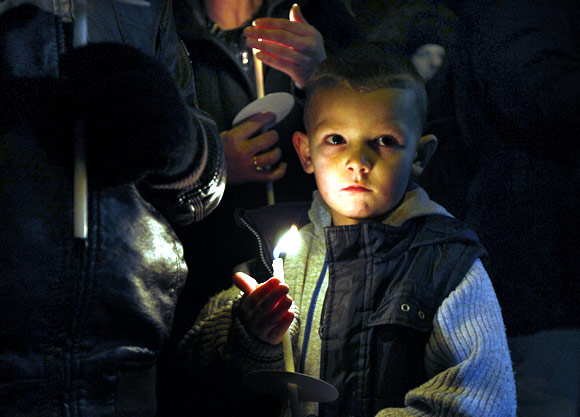 Five year old Jason Ward holds a candle alongside other children during the vigil at Salford