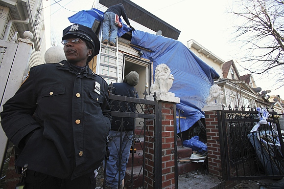 A New York City police officer stands outside a residence that was hit by a firebomb