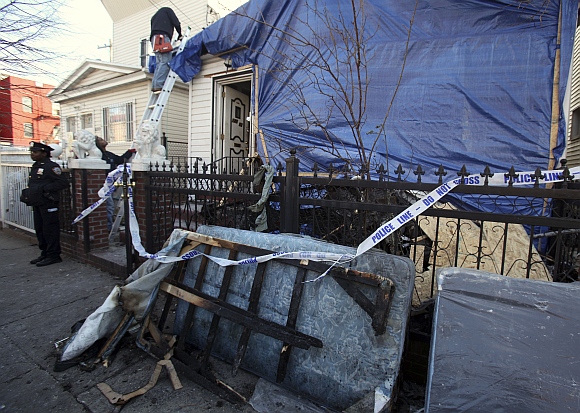 A New York City police officer stands outside a residence that was hit by a firebomb in the Queens borough of New York