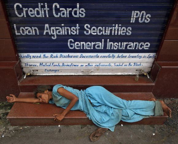 A homeless woman sleeps on the stairs of a closed brokerage office in Mumbai
