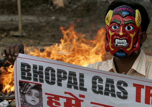 An activist wearing mask holds banner during a protest against the Bhopal gas disaster verdict in Bhopal