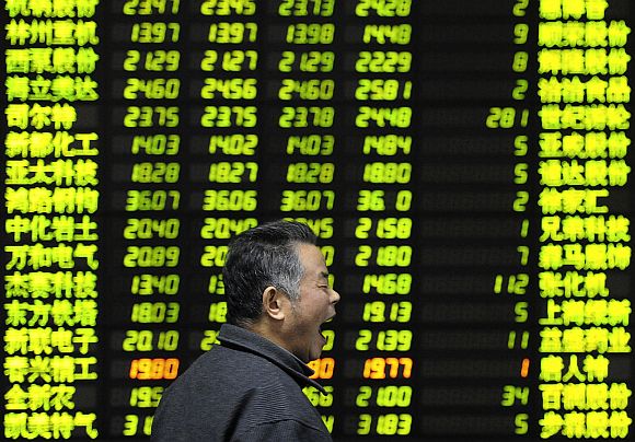 An investor yaws as he walks past an electrical board showing stock information at a brokerage house in Nanjing, China