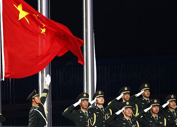Soldiers salute as they raise China's national flag during a ceremony in Guangzhou