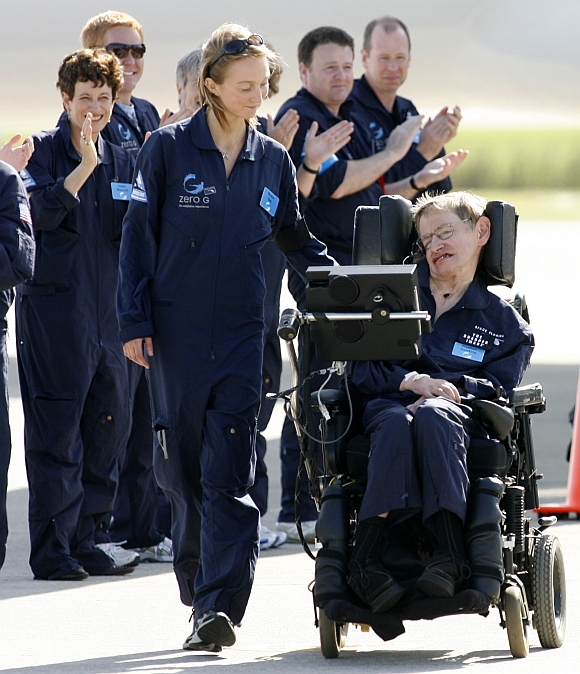 Hawking is wheeled by the people who took part in a ZERO-G flight with him at Kennedy Space Center in Cape Canaveral, Florida