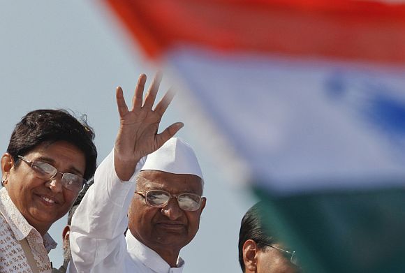 Anna Hazare with Kiran Bedi wave from a vehicle during a rally in Mumbai