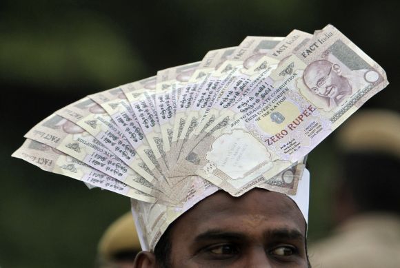 A supporter of social activist Hazare wears a cap lined with fake currency notes while attending a public meeting in Chennai