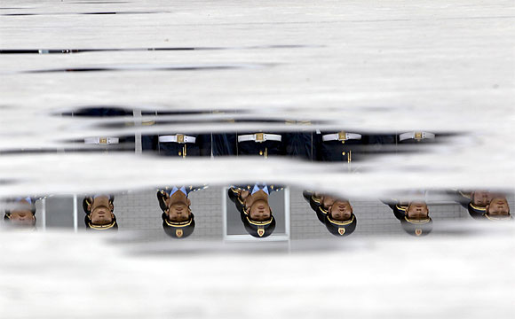 Soldiers from the honour guards of the Chinese People's Liberation Army are reflected in puddles of water