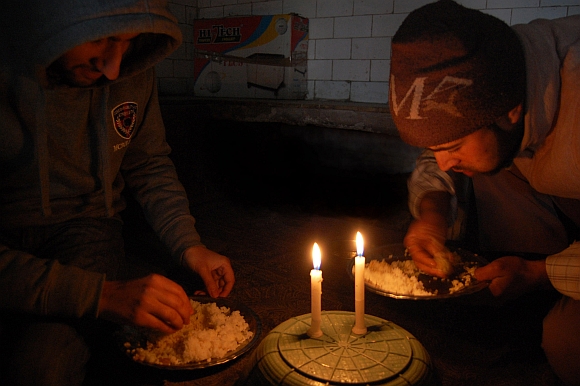 A Kashmiri family struggles to have its meal in candle light