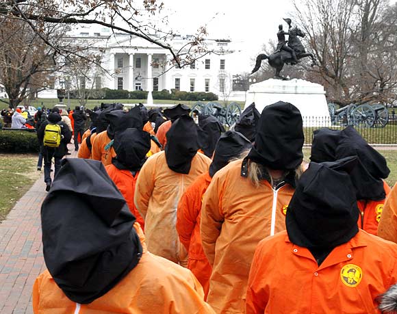 Protesters seeking the closure of the Guantanamo Bay detention facility wear orange jumpsuits and black hoods as they demonstrate outside the White House in Washington, DC