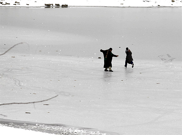 Kashmiri boys play on the semi-frozen layer of a water reservoir on a cold day on the outskirts of Srinagar