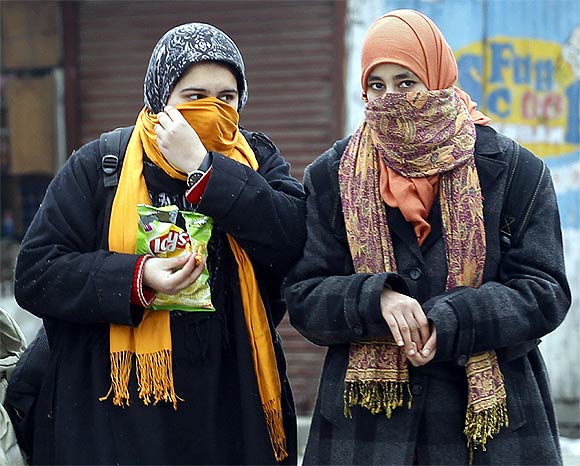 Kashmiri school girls cover their faces and heads to protect themselves from the extreme cold