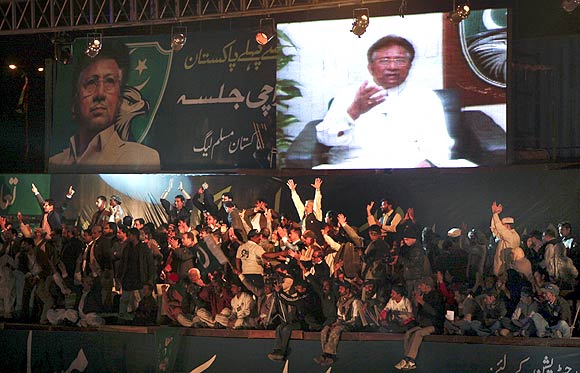 All Pakistan Muslim League supporters watch a screen broadcasting a speech by their party president Pervez Musharraf