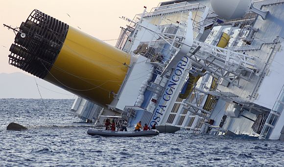 Rescuers stand in a boat next to the Costa Concordia cruise ship
