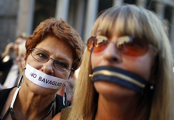 Women, who put a zip and a tape on their mouths, protest against a privacy law in downtown Rome