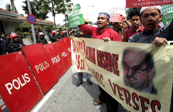 Protesters hold placards and shout slogans during a demonstration against Salman Rushdie