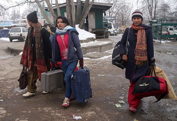 Stranded tourists walk to board the special IAF aircraft, in Srinagar, on Saturday