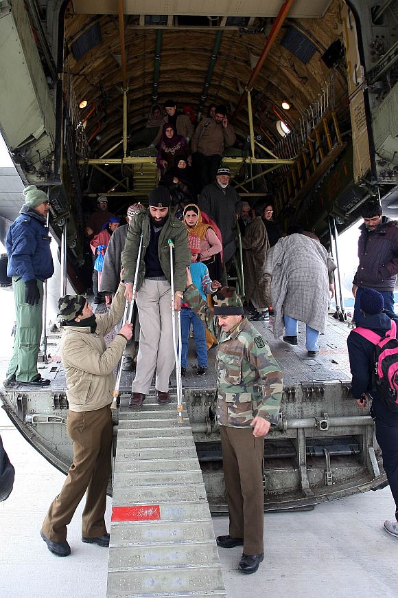 Defence personnel help a handicapped civilian disembark at Jammu air base
