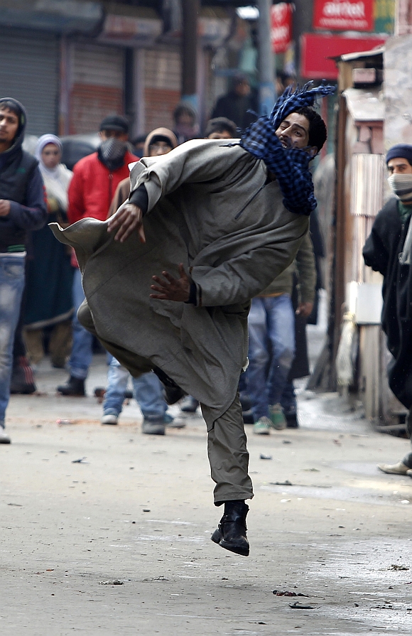A Kashmiri protester throws stones toward Indian police during a protest in Srinagar