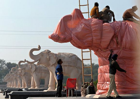 Election Commission-appointed workers cover the statues of elephants, which also happen to be the ruling Bahujan Samaj Party's election symbol, in Lucknow