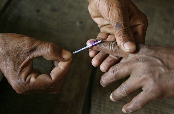 A polling officer applies ink on the finger of a voter at a polling station in Mohan Sarai, UP, in an earlier election