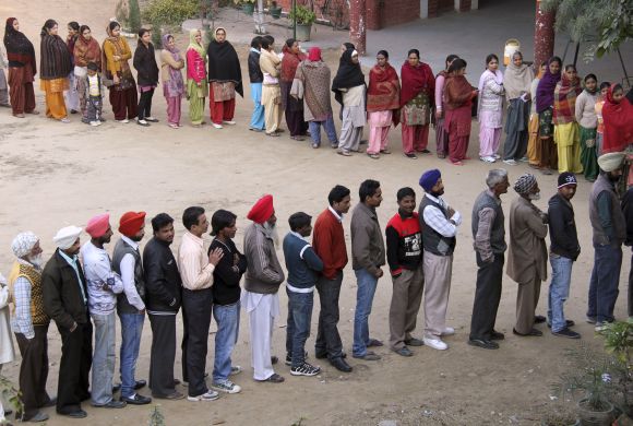 Voters line up to cast their ballots outside a polling station at Banur in Punjab, on Monday