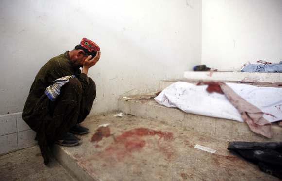 A man mourns next to his dead relative at a morgue, after his body was recovered from the site of a double suicide bombing in Quetta