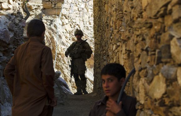 A US soldier looks back down an alleyway during patrol in Pech River Valley of Kunar Province in Afghanistan