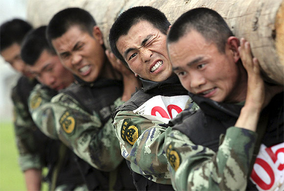 Chinese paramilitary police react as they carry a log on their shoulders during a training at a military base in Nanjing, Jiangsu province