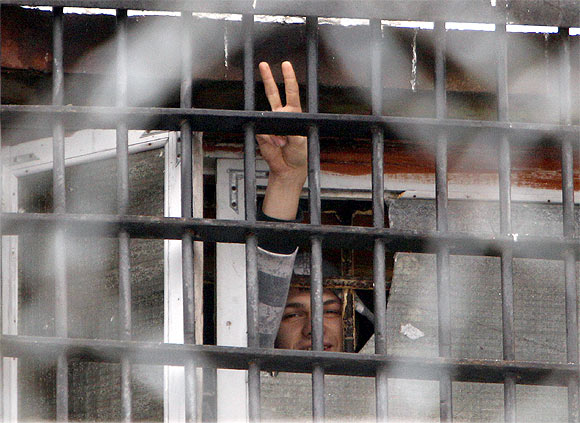 A Belarussian detainee arrested in protests gestures from a prison cell at a detention centre in Minsk