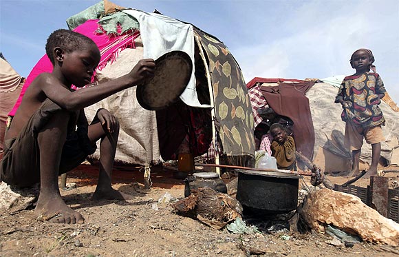 An internally displaced child prepares fire outside their makeshift shelter at a temporary camp in Hodan district of Somalia's capital Mogadishu