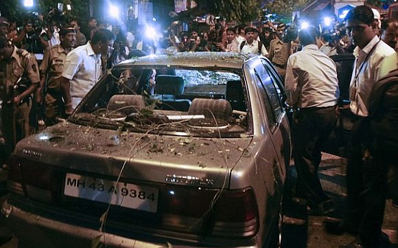 Policemen surround a vehicle which was damaged at the site of an explosion
