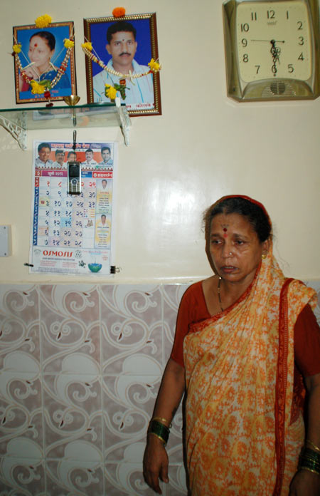 Tushar's mother standing under the portraits of her dead daughter and son Tushar