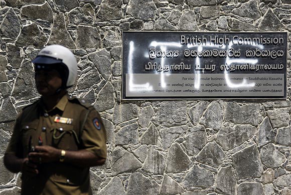 A policeman stands in front of a sign outside the British High Commission that has been spray-painted LTTE in Colombo