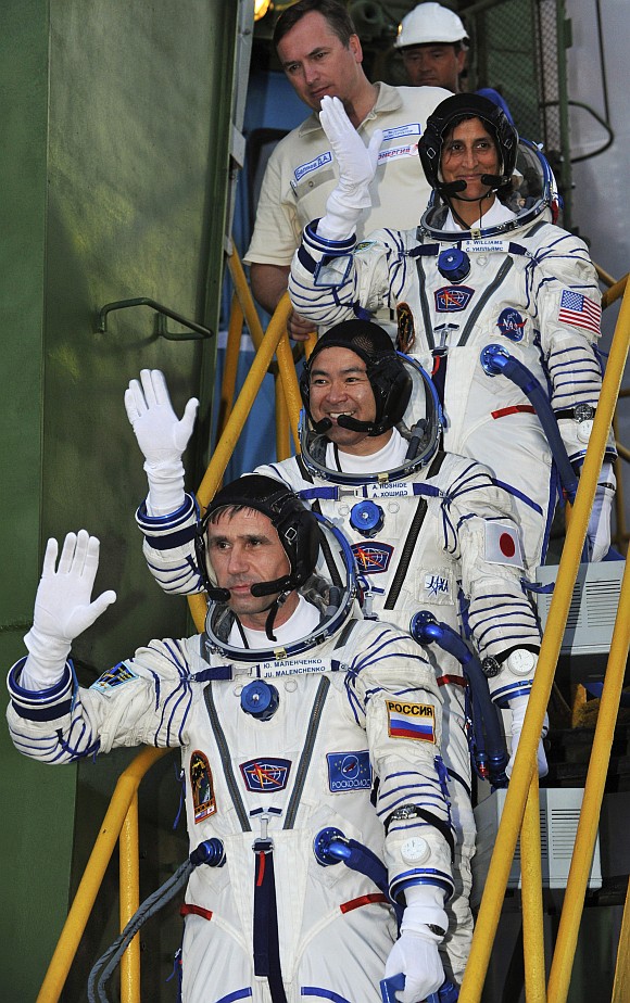 ISS crew members Russian cosmonaut Yuri Malenchenko (bottom), Japanese astronaut Akihiko Hoshide (centre) and US astronaut Sunita Williams wave as they board the Soyuz TMA-05M spacecraft at Baikonur cosmodrome