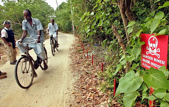 Sri Lankans cycle near a minefield in Irupalai, on the outskirts of Jaffna