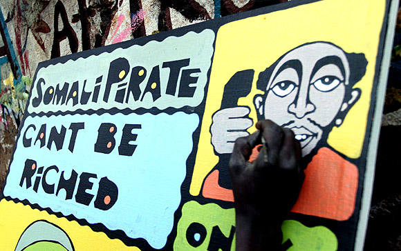 A Kenyan artist paints an anti-pirate graffiti on a wooden board at the sprawling Kibera slums in Kenya's capital Nairobi
