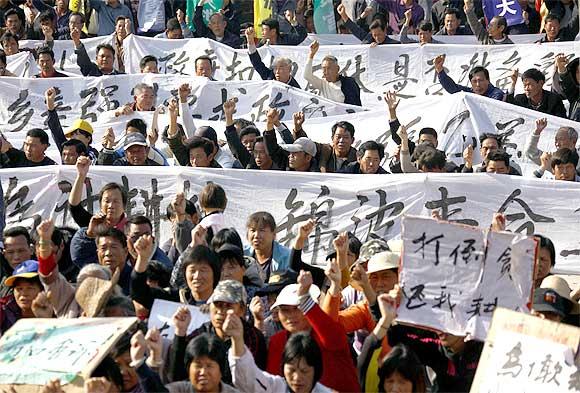 Residents raise their fists as they chant slogans and hold banners during a rally in the village of Wukan in Lufeng county, Guangdong province, China