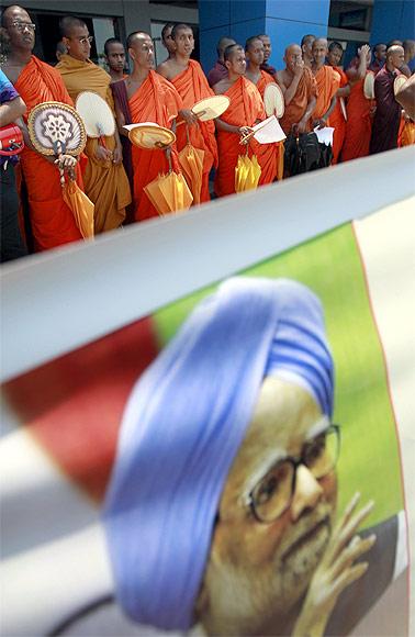 Buddhist monks stand near an image of Dr Singh