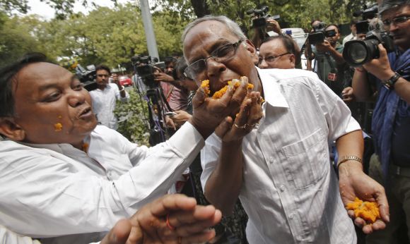 Congress supporters eat sweets distributed among themselves as they celebrate the election of their leader Pranab Mukherjee as the new president in New Delhi
