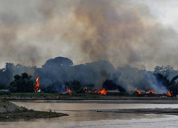 Flames erupt from huts built on the banks of river Gourang during violence near Kokrajhar town in Assam