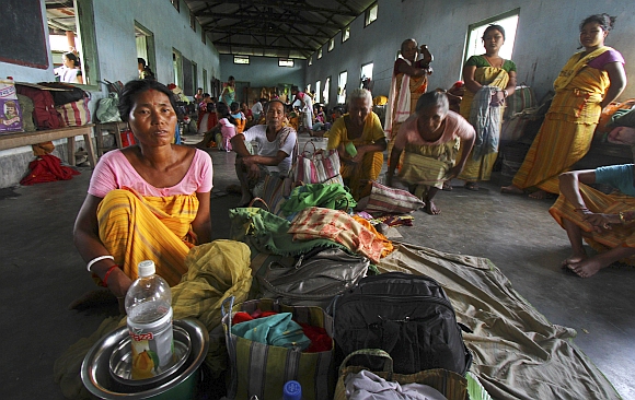 Villagers affected by the ethnic riots sit with their belongings inside a relief camp near Goshaigaon town, in Assam