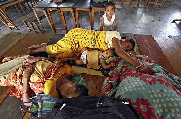 Villagers affected by ethnic riots rest inside a relief camp along with their children at Bijni town in Assam