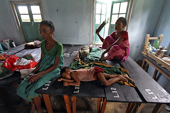 Villagers affected by ethnic riots rest inside a relief camp with their children at Bijni in Assam