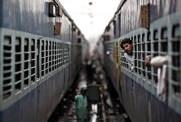 A passenger looks through the window of a train as he waits for electricity to be restored at a railway station in New Delhi.